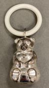 Vintage white metal baby rattle and teething ring in the form of a bear.