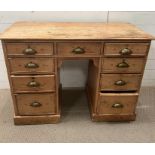 A pine knee hole desk, flanked with drawers and brass shell handles (H77cm W108cm D50cm)
