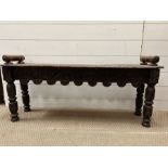 An oak carved low stool with carved handles to each end