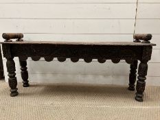 An oak carved low stool with carved handles to each end