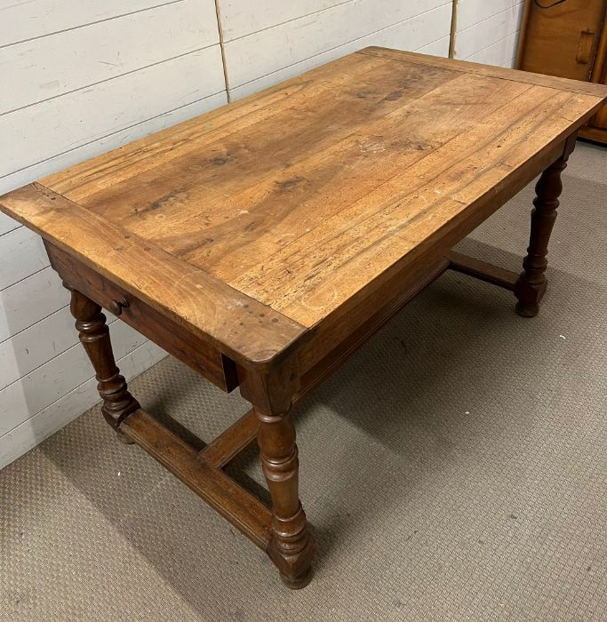 A farmhouse table with drawer to one end on turned legs and centre stretcher (H74cm W130cm D78cm)