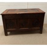 An oak coffer with three panelled hinged lid and carved panelled front and sides raised on block