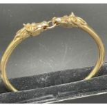 A 9ct gold horse themed bangle., Approximate total weight 41.5g, with two horse heads.