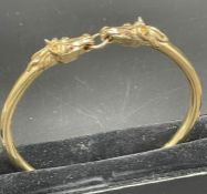 A 9ct gold horse themed bangle., Approximate total weight 41.5g, with two horse heads.