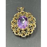 A gold pendant with central purple stone (untested, approximate weight 9.6g)