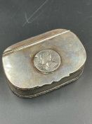 A white metal pill box with inset coin to lid