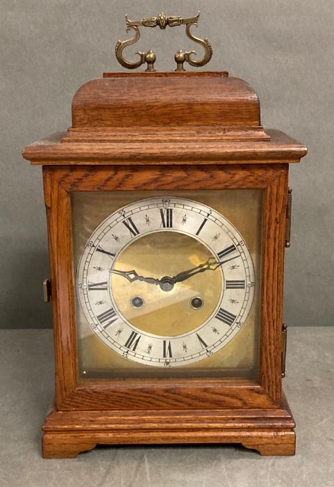 An eight day mantel clock with brass face in mahogany box with brass carrying handle.