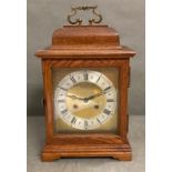 An eight day mantel clock with brass face in mahogany box with brass carrying handle.