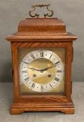 An eight day mantel clock with brass face in mahogany box with brass carrying handle.