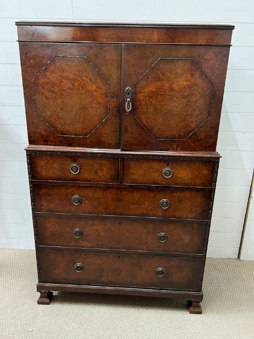 A linen press with panelled doors opening up to shelves with a chest of drawers under (H152cm