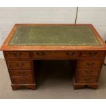 A pedestal desk with green leather top and brass drop handles (H78cm W121cm D 61cm)