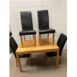 A kitchen table with four faux leather high back chairs