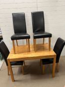 A kitchen table with four faux leather high back chairs