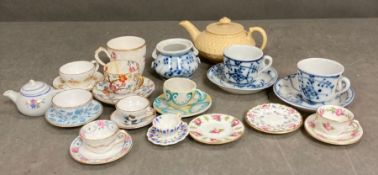 A large selection of miniature tea cups and saucers, various makers and ages