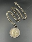 A 1900 US silver dollar on a substantial silver chain and mount