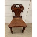 A Victorian hall chair with scroll moulded back plank seat raised on turned legs