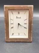 A silver faced clock marked "Harrods"