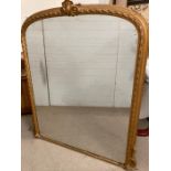 A giltwood arched over mantle mirror with a carved cartouche to centre and foxed glass (150 cm x