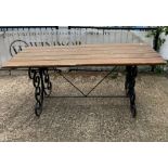 A wrought iron plank top garden table with scrolling sides (H76cm W183cm D76cm)