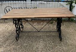 A wrought iron plank top garden table with scrolling sides (H76cm W183cm D76cm)