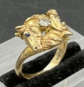 A 9ct gold ring, horse themed ring, a diamond set between two horse heads. Size K1/2 and approximate