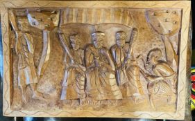 A carved wooden plaque of a tribal scene (55cm x 35cm)