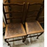 A pair of yew ladder back chairs with wicker seats and scroll cabriole legs