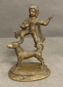 A bronze of an Indian acrobat standing on a hound