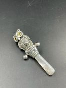 A silver babies rattle in the form of an owl, glass inset eyes