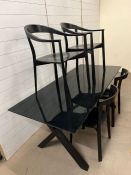 A black glass top dinning table with wooden X frame legs and six stylist chairs (H72cm W180cm