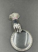 A silver pendant in the form of a hand and spy glass