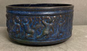 A blue glazed terracotta pot with decoration to side
