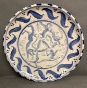 A signed charger by the potter Peter Cutting painted blue and white with Hares boxing (36cm