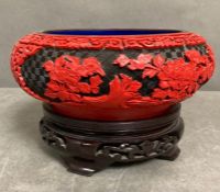 A chinese cinnabar laquer bowl on a wooden stand