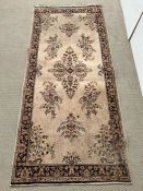 A floral medallion rug with beige ground and dark boarder, hand knotted 214cm x 91cm