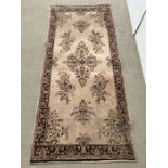 A floral medallion rug with beige ground and dark boarder, hand knotted 214cm x 91cm