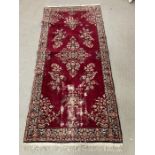 A floral medallion rug with red ground and dark boarder, hand knotted 210cm x 90cm