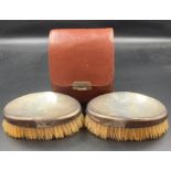 A pair of silver backed brushes in a leather case. Hallmarked for London 1946, makers mark for