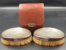 A pair of silver backed brushes in a leather case. Hallmarked for London 1946, makers mark for