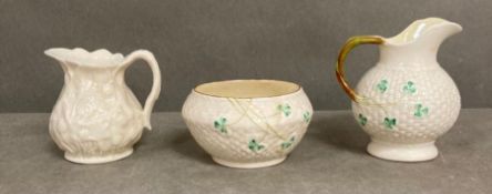 Two Belleek milk jugs and a Belleek sugar bowl