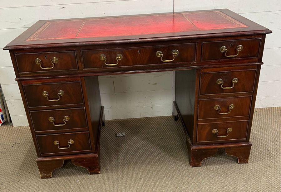 A pedestal desk with red leather top and brass drop handles (H78cm W121cm D60cm)