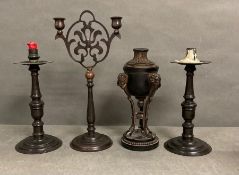 A selection of three candlesticks and a candle stick urn with cloven feet
