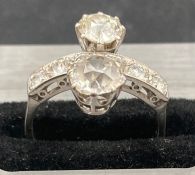 An Art Deco style double diamond ring, set in platinum. The main diamonds weigh approx 1ct and 0.