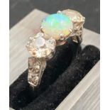 A white opal and diamond three stone ring mounted in platinum. Central opal weighs approx 1 ct,