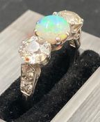 A white opal and diamond three stone ring mounted in platinum. Central opal weighs approx 1 ct,