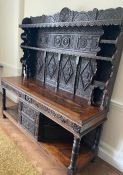 A heavy carved oak dresser with Tudor rose panelling carved figures of Henry VII further carved