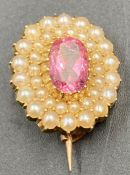 A small 9ct gold brooch with seed pearls and central amethyst style stone.