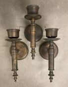 A trio of wall mounted brass candle holders