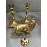 A pair of brass candlesticks along with a dog