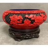 A chinese cinnabar laquer bowl on a wooden stand